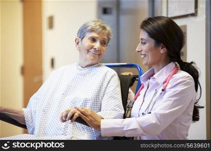 Senior Female Patient Being Pushed In Wheelchair By Doctor