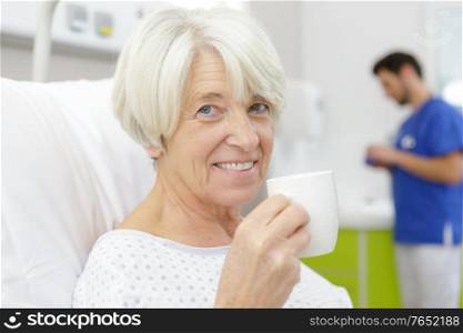 senior female patient drinking coffee on hospital bed