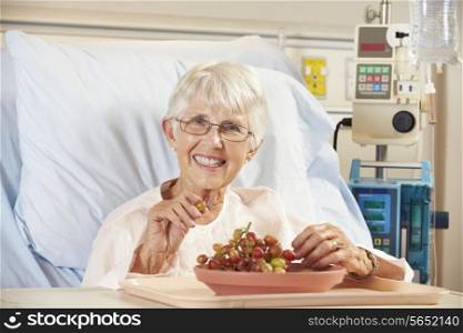 Senior Female Patient Eating Grapes In Hospital Bed