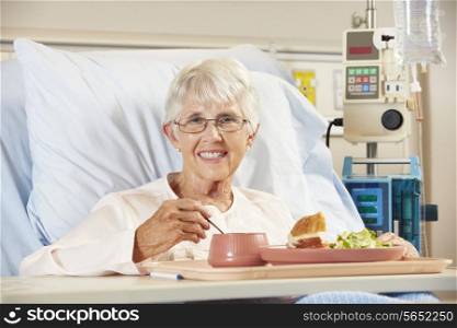 Senior Female Patient Eating Meal In Hospital Bed