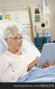 Senior Female Patient Relaxing In Hospital Bed With Digital Tablet