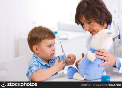 Senior female pediatrician playing with child at doctors office.