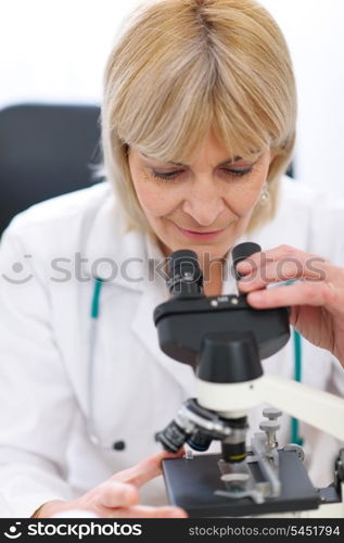 Senior female researcher looking in microscope