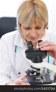 Senior female researcher looking in microscope