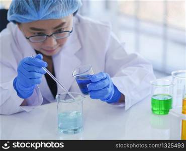 Senior female scientists working alone in the lab Preparing to mix the two fluids in a beaker for a biological chemical science experiment to achieve the expected results.