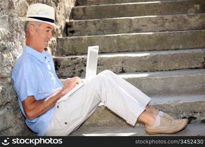 senior gentleman working on laptop outdoors