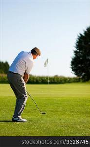 Senior golfer doing a golf stroke, he is playing on a wonderful summer afternoon