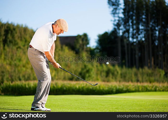 Senior golfer doing a golf stroke, he is playing on a wonderful summer afternoon