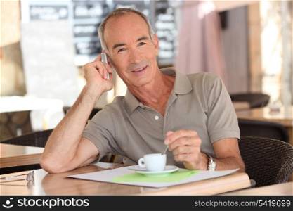 Senior having an expresso while talking on his cellphone