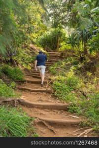 Senior hiker walsk up the steep Kalalau trail from Ke&rsquo;e Beach on north coast of Kauai. Steep steps in the dirt path of Kalalau trail on Na Pali coast of Kauai