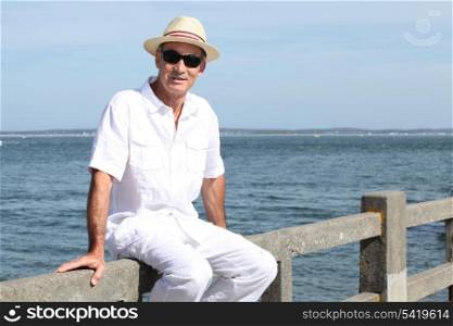 Senior in a straw panama hat sitting by the water