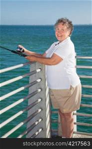 Senior lady having a great time fishing off a pier.