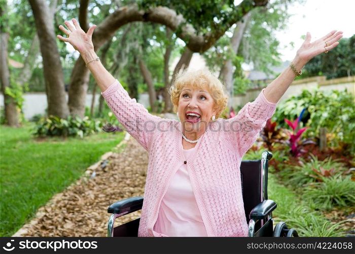Senior lady in wheelchair is ecstatic as she celebrates freedom from pain.