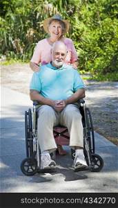 Senior lady pushing her husband in his wheelchair.