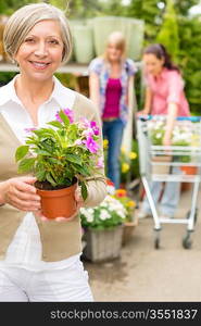 Senior lady shopping for flowers at garden centre smiling