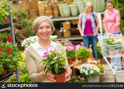 Senior lady shopping for flowers at garden centre smiling