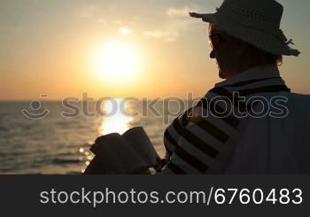 Senior lady silhouette by the sea at sunset