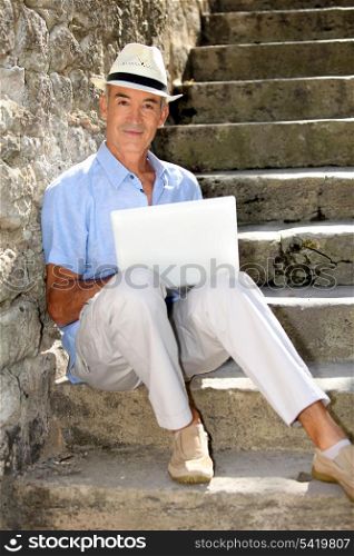 senior ma n relaxing outdoors with his laptop