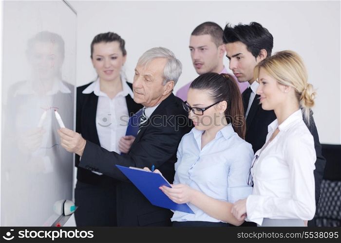 Senior male business man giving a presentation at a meeting at modern light office on a table board