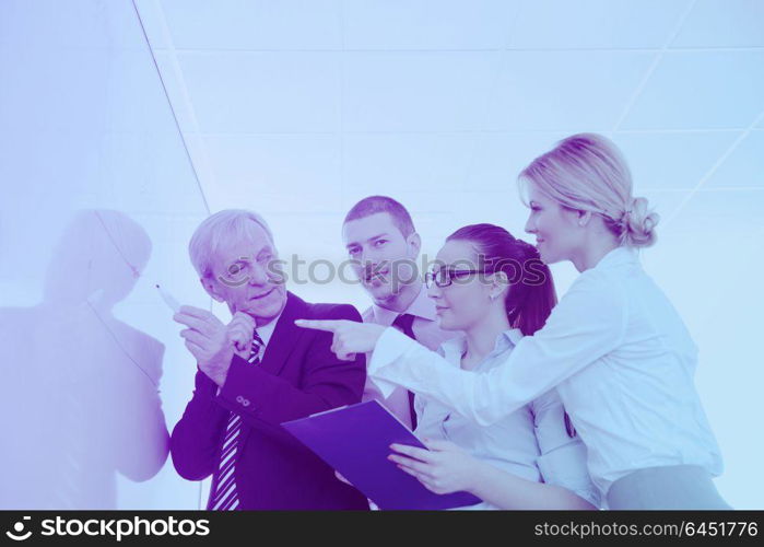 Senior male business man giving a presentation at a meeting at modern light office on a table board