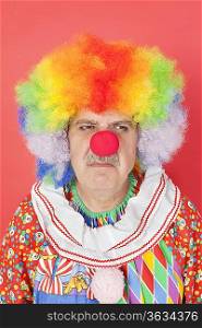 Senior male clown frowning over red background