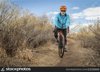 senior male cyclist is riding a gravel bike on a single track trail in winter or fall scenery - Arapaho Bend Natural Area in Fort Collins, Colorado