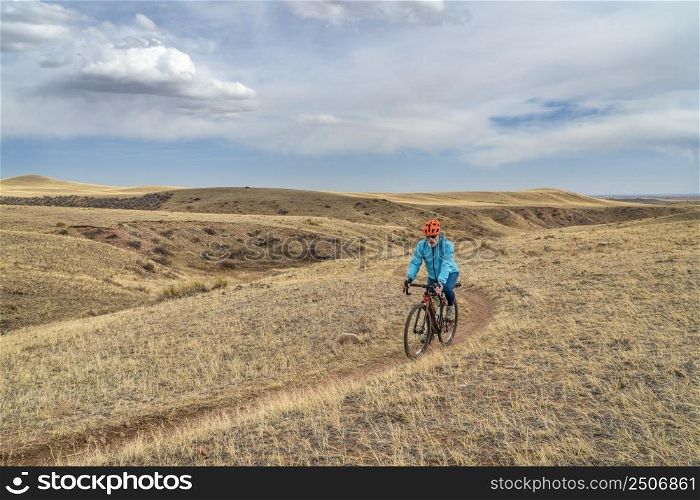 senior male cyclist is riding a gravel bike on a single track trail in Colorado foothills in early spring scenery, Soapstone Prairie Natural Area