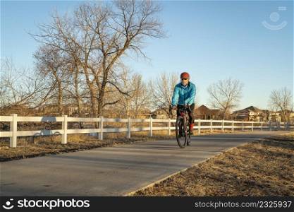 senior male cyclist is riding a gravel bike on one of numerous bike trails in northern Colorado in fall or winter scenery - Poudre River Trail near WIndsor