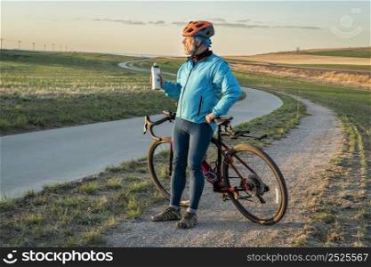 senior male cyclist with a gravel bike is taking a break and watching sunset when riding biking trail Colorado foothills between Fort Collins and Loveland, early spring scenery