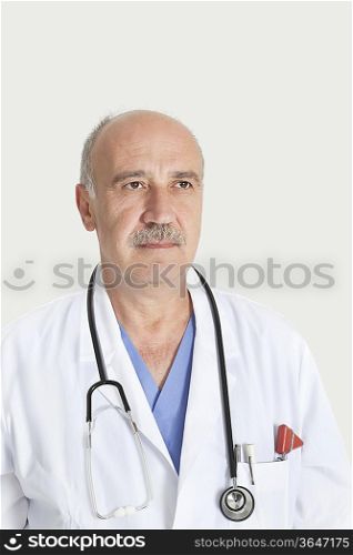 Senior male doctor with stethoscope over gray background