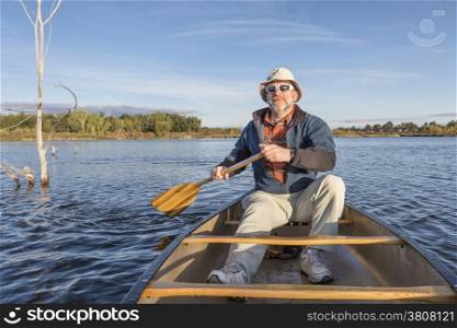 senior male enjoying morning sun on lake in a canoe, Riverbend Ponds Natural Area, Fort Collins, Colorado