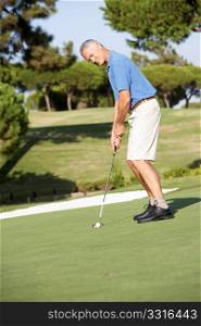 Senior Male Golfer On Golf Course Putting On Green