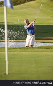 Senior Male Golfer Playing Bunker Shot On Golf Course