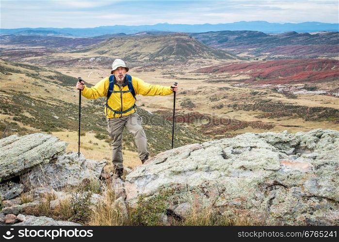 senior male hiker reaching top of a rock cliff and gasping for air, REd MOuntain Open Space near Fort Collins, Colorado, early fall