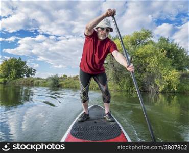 senior male paddler enjoying workout on stand up paddleboard (SUP), calm lake in Colorado, late summer
