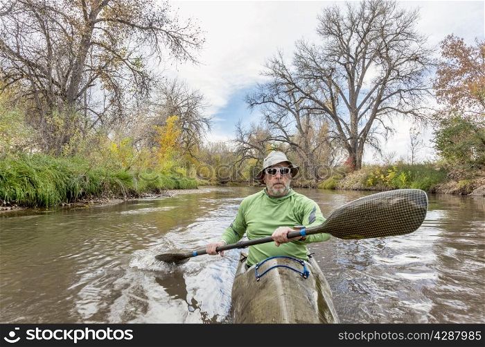 senior male paddler training in a fast sea kayak used in adventure racing, fall scenery, Poudre RIver in Fort Collins, Colorado, bow view