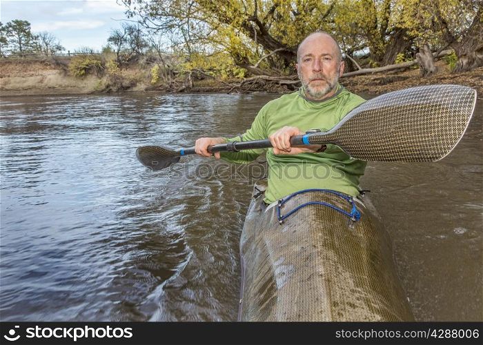 senior male paddler training in a fast sea kayak used in adventure racing, fall scenery, Poudre RIver in Fort Collins, Colorado, bow view