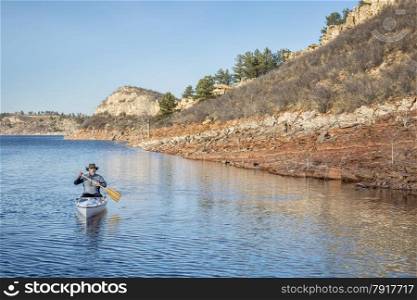 senior male paddling a decked expedition canoe on a mountain lake - Horsetooth Reservoir near Fort Collins, Colorado, early spring scenery