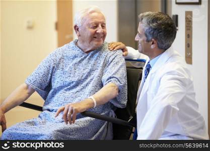 Senior Male Patient Being Pushed In Wheelchair By Doctor