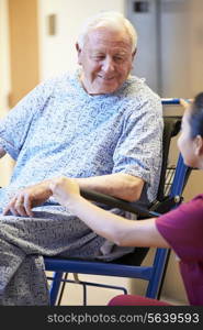 Senior Male Patient Being Pushed In Wheelchair By Nurse