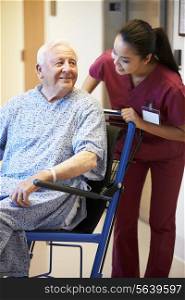 Senior Male Patient Being Pushed In Wheelchair By Nurse