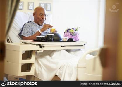 Senior Male Patient Enjoying Meal In Hospital Bed