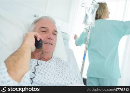 senior male patient using phone in hospital bed