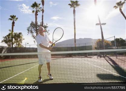 Senior male tennis player holding racket on court
