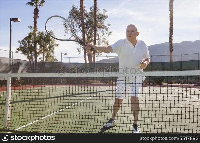 Senior male tennis player preparing to serve on court