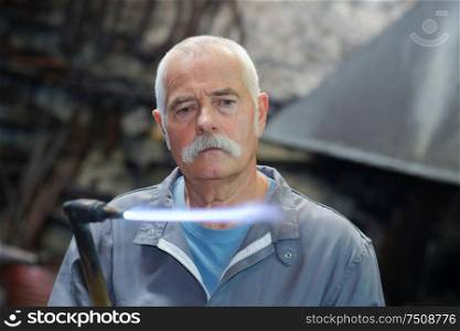 senior male worker using gas torch