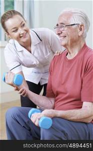 Senior Male Working With Physiotherapist Using Weights