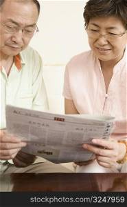 Senior man and a mature woman reading a newspaper