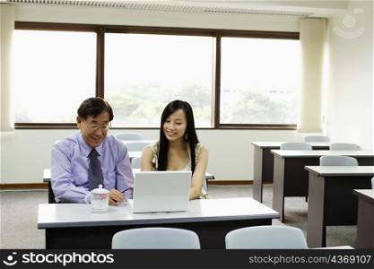 Senior man and a young woman using a laptop