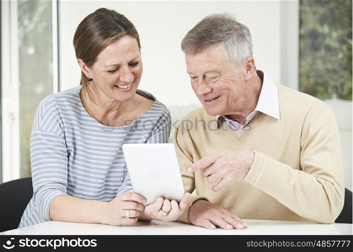 Senior Man And Adult Daughter Looking At Digital Tablet Together